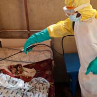 A health care worker sprays around a baby suspected of dying of Ebola in Beni, North Kivu Province of Democratic Republic of Congo, Dec. 13. | REUTERS