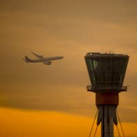 A passenger aircraft passes a control tower at Heathrow Airport on Dec. 24. | BLOOMBERG