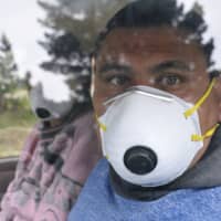 A fruit harvester wearing a face mask looks out the window of his car in Epuyen, Argentina, Jan. 11. An Argentine judge has ordered 85 residents of a remote Patagonian town to stay in their homes for at least 30 days to help halt an outbreak of hantavirus. | AP