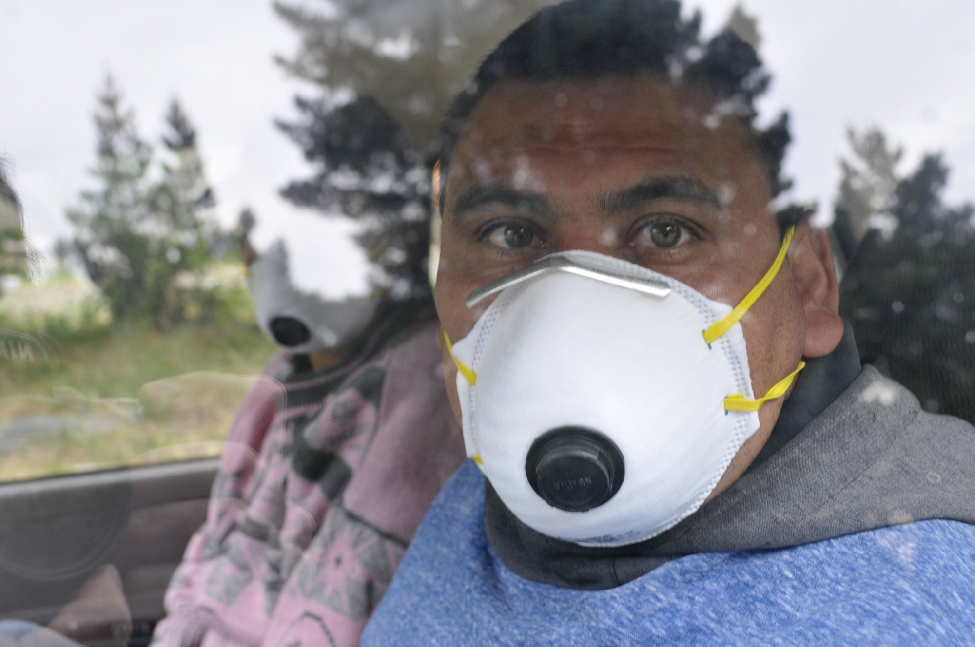 A fruit harvester wearing a face mask looks out the window of his car in Epuyen, Argentina, Jan. 11. An Argentine judge has ordered 85 residents of a remote Patagonian town to stay in their homes for at least 30 days to help halt an outbreak of hantavirus. | AP