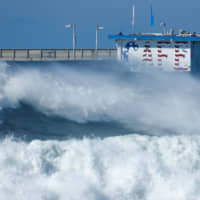 High waves sweep past a cafe on a pier at Ocean Beach in San Diego, California, on Wednesday. | REUTERS