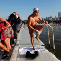 A swimmer wipes his legs dry on Saturday after he took part in a competition in a pool carved out of the frozen Songhua River. The event was part of the annual ice festival in the city of Harbin, in the northern Chinese province of Heilongjiang. | REUTERS
