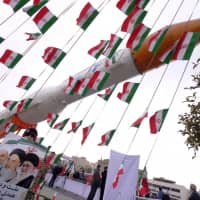 A boy holding a placard with pictures of (from left) President Hassan Rouhani, the late founder of the Islamic Revolution Ayatollah Ruhollah Khomeini and Iran Supreme Leader Ayatollah Ali Khamenei poses in front of a model of a Simorgh satellite-carrier rocket during a ceremony marking the 37th anniversary of the Islamic Revolution, in Tehran in 2016. | AHEB HOMAVANDI / TIMA / VIA REUTERS