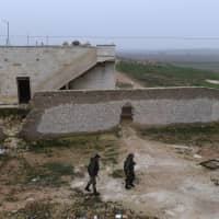 Members of the Syrian regime forces walk near buildings in the southern countryside of the northern Kurdish-controlled city of Manbij on Sunday. The unexpected U.S. pullout announcement left Syria\'s Kurds scrambling to find a new ally in the Damascus regime, as they feared losing U.S. support would leave them exposed to a long-threatened Turkish assault. | AFP-JIJI