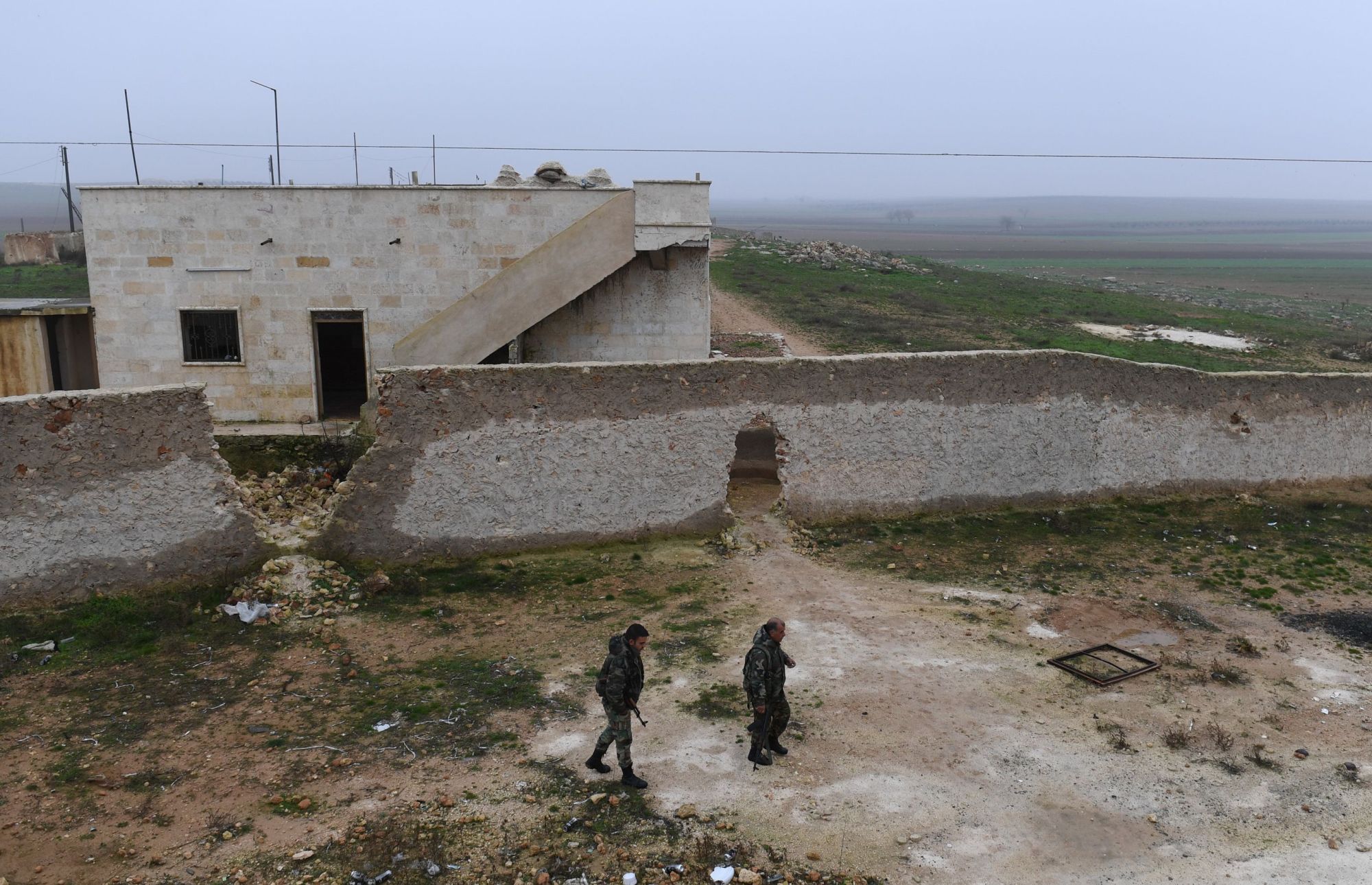 Members of the Syrian regime forces walk near buildings in the southern countryside of the northern Kurdish-controlled city of Manbij on Sunday. The unexpected U.S. pullout announcement left Syria's Kurds scrambling to find a new ally in the Damascus regime, as they feared losing U.S. support would leave them exposed to a long-threatened Turkish assault. | AFP-JIJI