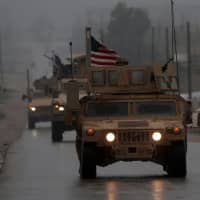 U.S. military vehicles are seen in Syria\'s northern city of Manbij Sunday. President Donald Trump appeared to backtrack on Monday on shock plans for an immediate pullout of U.S. troops from Syria, but said his drive to end American involvement in wars made him a \"hero.\" | AFP-JIJI
