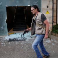 Serge Medic, the Swiss owner of a security company, carries his pistol as he walks at the scene where explosions and gunshots were heard at the Dusit hotel complex in Nairobi Jan. 15. | REUTERS