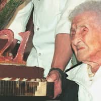 Jeanne Calment, French pensioner and the world\'s oldest person, looks at her birthday cake upon turning 121 years old during a ceremony held in her honour at Arles City Hall in the southern France in 1996. What if Calment\'s longevity record was a fraud? Russian researchers have concluded an incredible sleight of hand between the Frenchwoman and her daughter, provoking interest and controversy in the scientific community. Jeanne Calment died at the age of 122 years and 164 days in 1997 &#8212; a world record of longevity of all genders. | AFP-JIJI