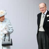 Britain\'s Queen Elizabeth IIand Prince Philip, Duke of Edinburgh, wait for the carriage carrying Princess Eugenie of York and her husband, Jack Brooksbank, to pass at the start of the procession after their wedding ceremony at St. George\'s Chapel, Windsor Castle, in Windsor, England, in October. | AFP-JIJI