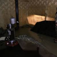 A Syrian refugee woman is seen in her flooded tent in Bar Elias town, in the Bekaa valley of Lebanon Monday. | REUTERS