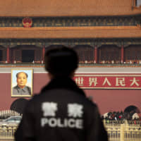 A police officer stands guard in front of a portrait of former Chinese leader Mao Zedong at Tiananmen Square in Beijing, China last February.  | Bloomberg