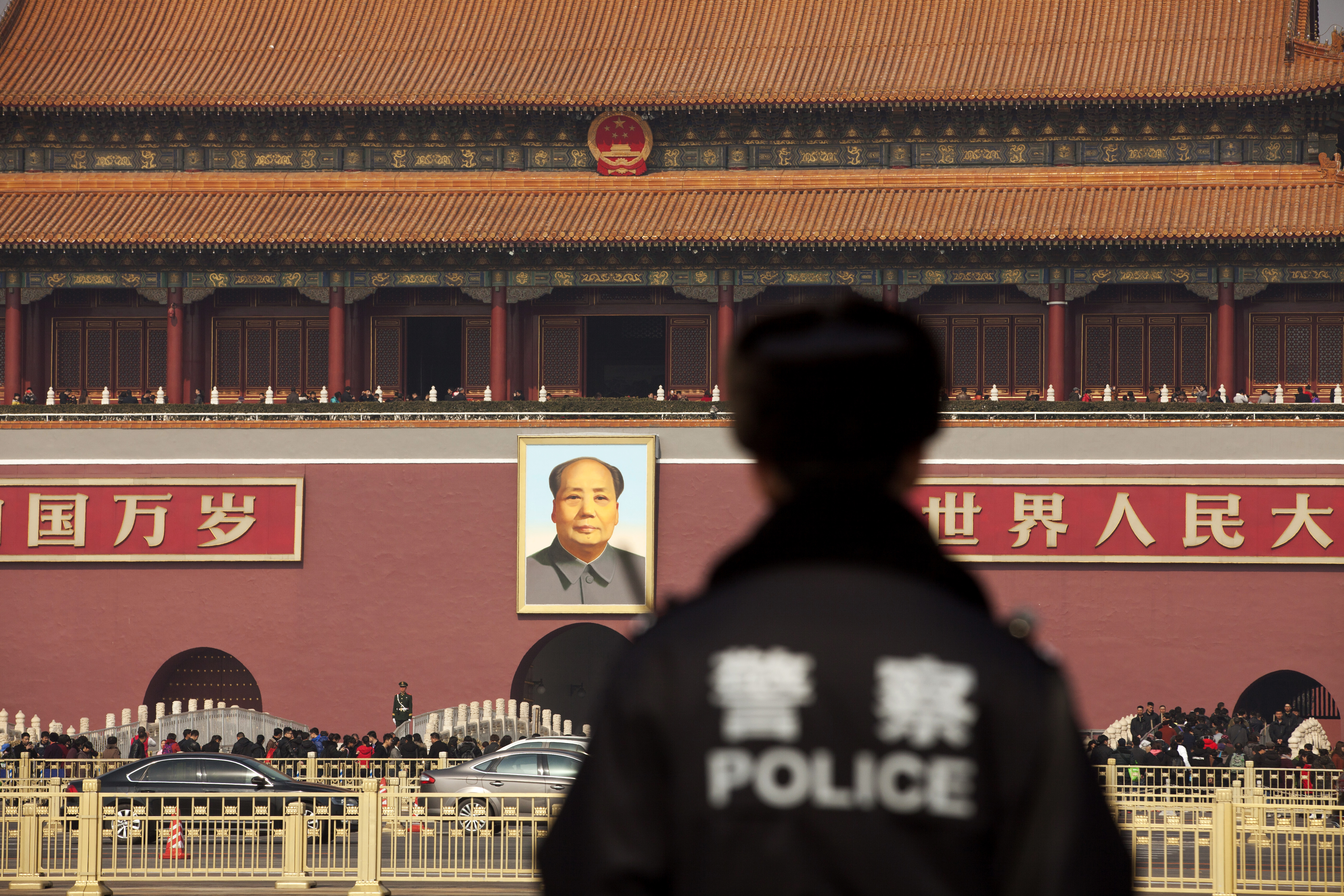 A police officer stands guard in front of a portrait of former Chinese leader Mao Zedong at Tiananmen Square in Beijing, China last February.  | Bloomberg