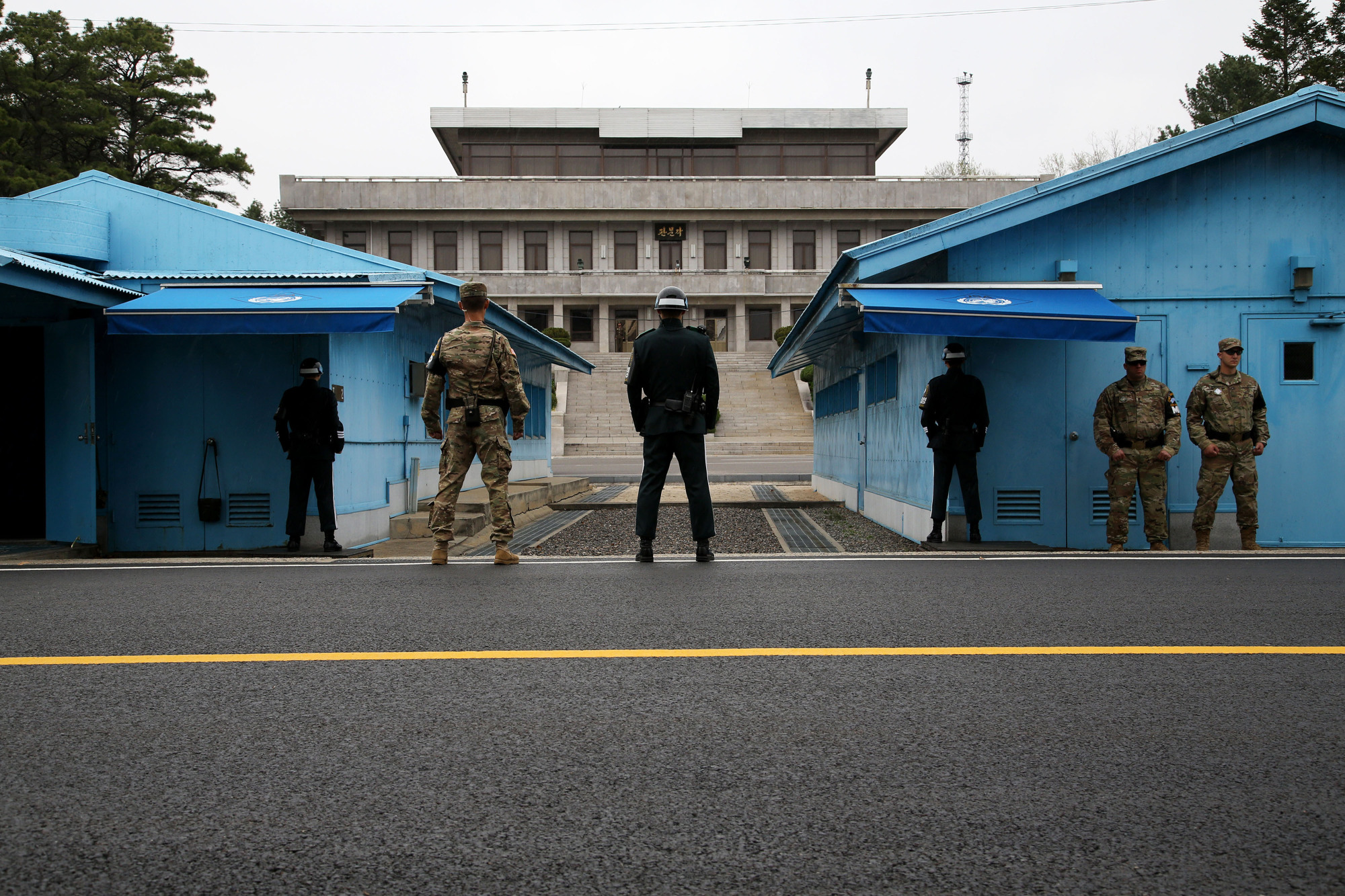 U.S. and South Korean soldiers stand guard next to the meeting rooms that straddle the border between the two Koreas in the truce village of Panmunjom in the Demilitarized Zone in Paju, South Korea, in April 2017. | BLOOMBERG