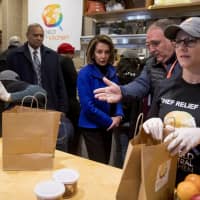 House Speaker Nancy Pelosi (center) and Chef Jose Andres (second from right) arrive to give out food at World Central Kitchen, the not-for-profit organization started by Chef Jose Andres, Tuesday in Washington. | AP