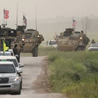 Kurdish fighters from the People\'s Protection Units (YPG) head a convoy of U.S. military vehicles in the Syrian town of Darbasiya, next to the Turkish border, in April 2017. | REUTERS