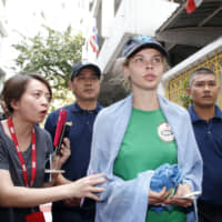 Anastasia Vashukevich speaks to journalists while being escorted by Thai immigration officers from the Immigration Detention Center in Bangkok on Thursday. | AP
