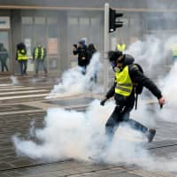 A protester returns a tear gas canister during a demonstration of the \"yellow vests\" movement in Strasbourg, France, Saturday. | REUTERS