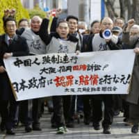 Plaintiffs walk toward the Osaka District Court on Tuesday before a ruling in a lawsuit filed by Chinese citizens seeking compensation for forced labor during World War II. | KYODO