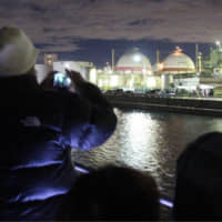 Tourists taking part in a night cruise in Yokkaichi, Mie Prefecture, take pictures of a factory complex lit up in the dark. | CHUNICHI SHIMBUN