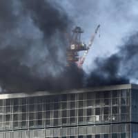 Black smoke billows from a high-rise building under construction near JR Shimbashi Station in Tokyo on Friday. | KYODO