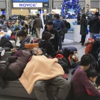 People who stayed overnight at New Chitose Airport in Hokkaido crowd the lobby of the airport Sunday morning after some 2.000 travelers were left stranded due to heavy snow that led to flight cancelations. | KYODO