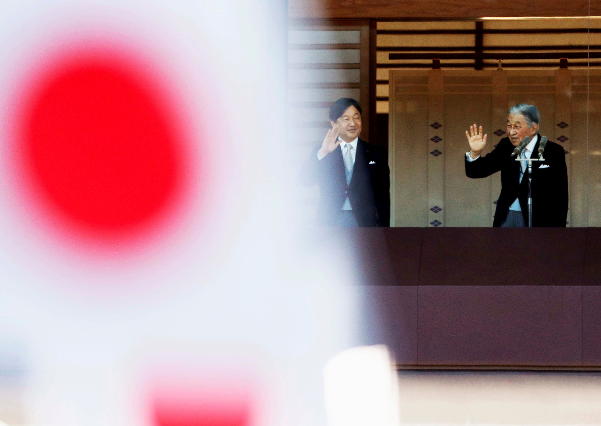 Emperor Akihito and Crown Prince Naruhito are seen behind Hinomaru flags as they wave to well-wishers during New Year's celebrations at the Imperial Palace in Tokyo on Jan. 2. | REUTERS