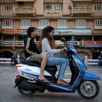 People ride an electric scooter in Ahmedabad, India, on Dec. 30. | REUTERS