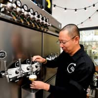Shimada pours a glass of kombucha at Oizumi Kojo’s kombucha brewery in Kawaguchi, Saitama Prefecture. | YOSHIAKI MIURA