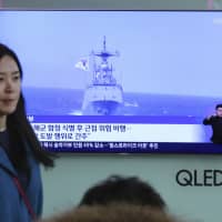 File footage of a South Korean warship is shown during a TV news program viewed at the main railway station in Seoul on Wednesday. | AP