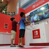 Children play a game on a Switch console at the Nintendo Check In game experience area of Terminal 1 at Kansai International Airport in Izumisano, Osaka Prefecture, last July. | BLOOMBERG