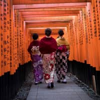 Tourists in kimono walk through the gates at Fushimi Inari Shrine in Kyoto on Dec. 9. | AFP-JIJI