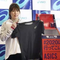 Saori Yoshida, a three-time Olympic wrestling champion, holds up a T-shirt she wore at the 2016 Rio de Janeiro Games. Yoshida is donating the shirt to a project launched Thursday by Asics Corp. to make uniforms for the Japanese Olympic and Paralympic teams by recycling sportswear items. | KYODO
