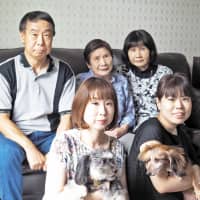 The Taguchi family includes (back row, from left) father Yuichi, grandmother Fujie, mother Chiyoko and, in the front row, sisters Reina and Ai. Reina holds Shishimaru and Ai holds the late Minnie, who was also an adopted pet. | AI TAGUCHI