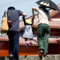 Three\'s company: A young family makes its way through the grounds of Shurijo Castle in Naha, Okinawa Prefecture, in June 2012. | ROB GILHOOLY