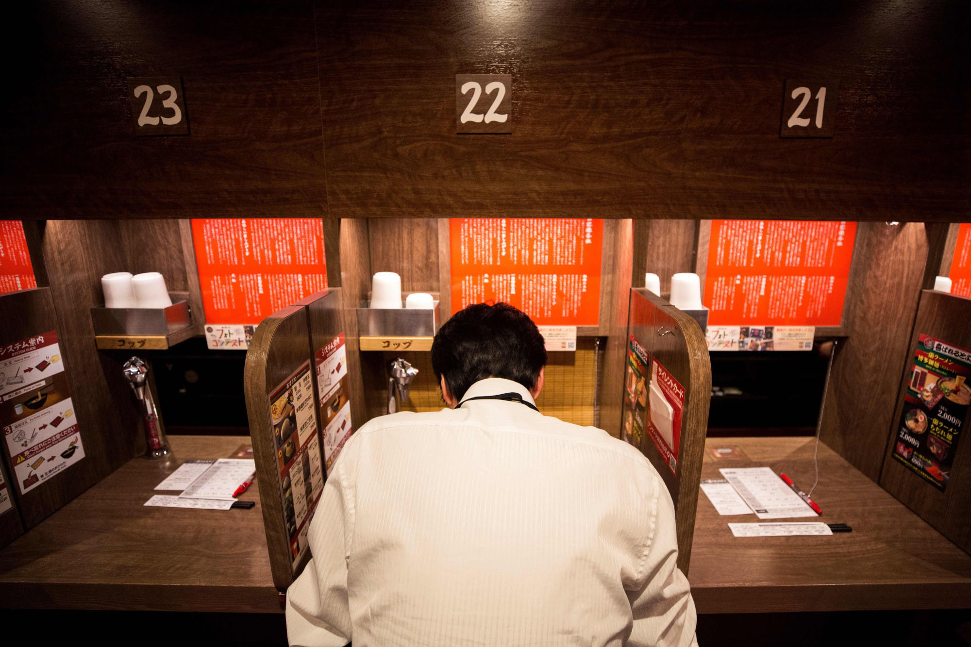 A customer in a partitioned booth eats ramen at a restaurant in Tokyo in 2018.