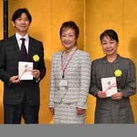 Hideki Asahi, executive sales officer and manager of the media enterprise department at The Japan Times (left), and Toshiko Hasegawa, president of the Japan National Student Association Fund (right), pose for a photo with Ikebana International Tokyo Founding Chapter President Misako Ishii. | YOSHIAKI MIURA