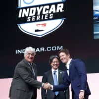IndyCar CEO Mark Miles (left), NTT executive vice president Tsuneshia Okuno (center) and 2018 series champion Scott Dixon shake hands during a news conference announcing IndyCar\'s title sponsorship deal with NTT on Tuesday in Detroit. | AP