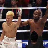 Mayweather lifts Nasukawa’s arm and waves to the crowd following the bout, which Mayweather won via technical knockout. | AP