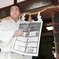 Georgian wrestler Tochinoshin poses with a new banzuke last June after winning promotion to ozeki. | KYODO