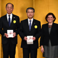 Masahiko Tanabe, vice-governor of Hiroshima Prefecture (left), and Keiji Abe, vice-governor of Hokkaido (center), receive a donation from Matelda Starace, chairperson of the Ikebana International Fair 2018 for victims of the torrential rains and floods in western Japan and the Hokkaido earthquake disaster at the Ikebana International 2019 New Year Luncheon at the Palace Hotel Tokyo on Jan. 16. | YOSHIAKI MIURA
