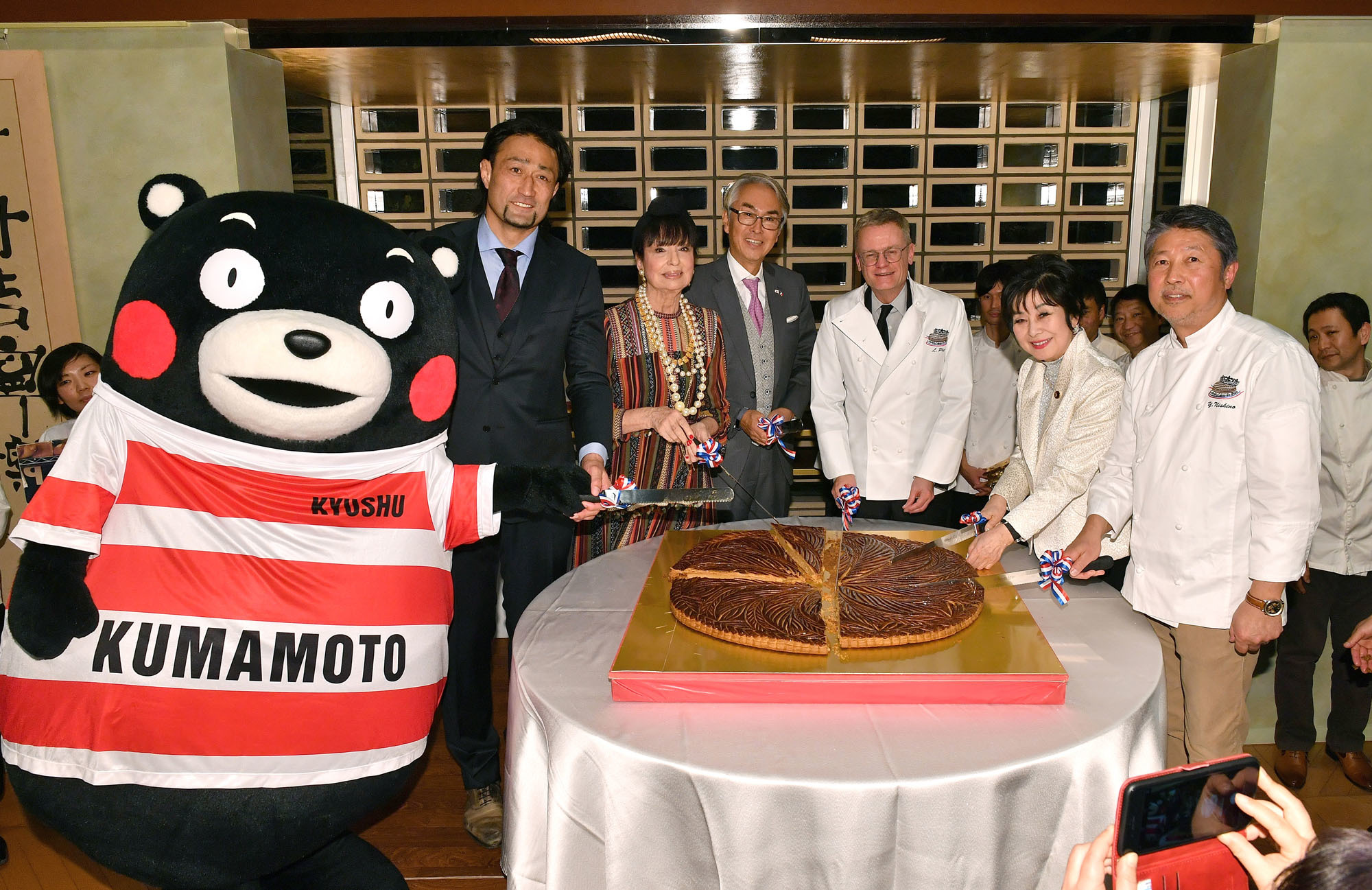 French Ambassador Laurent Pic (third from right) cuts a galette des rois, a cake traditionally served on Jan. 6 to celebrate the arrival of the Three Wise Men in Bethlehem before Jesus' birth, with (from left), Kumamon; Japan National Team rugby player and former Galette des Rois Ambassador Hitoshi Ono; essayist Francoise Morechand; Chairman of the Japan-France Parliamentary Friendship League Nobuteru Ishihara; House of Councillors member Akiko Santo; and Galette des Rois Club President Patissier Yukio Nishino at the ambassador's residence on Jan. 16. |  YOSHIAKI MIURA