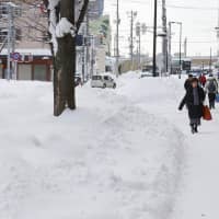 Pedestrians walk near Aomori Station in the prefectural capital on Wednesday after large areas of the Tohoku and Hokuriku regions were hit with heavy snow the previous day. The weather agency has warned of continued strong winds in many parts of the country. | KYODO