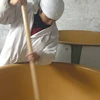 A brewer carefully prepares sake at a brewery in Fukushima Prefecture. | FUKUNOSAKE