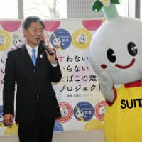 Keiji Goto, the mayor of Suita in Osaka Prefecture, speaks while standing with Suitan, the city\'s mascot, at an event Friday to launch a project by the city to persuade all of its officials to be non-smokers. Suita is eager to become a health-conscious city as it is promoting the Northern Osaka Health and Biomedical Innovation Town policy, with the hope of cultivating medical-related institutions and companies. | KYODO