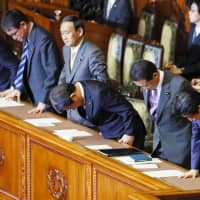 Prime Minister Shinzo Abe (right) and Finance Minister Taro Aso (second from right) bow at the Upper House on Thursday after the chamber enacted a &#165;3.04 trillion supplementary budget for fiscal 2018. | KYODO