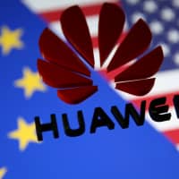 A 3D printed Huawei logo is placed on glass above displayed EU and U.S. flags in this illustration taken Jan. 29. | REUTERS
