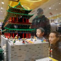A boy and his mother look at the Zhengyang Gate Tower of the Forbidden City made with Lego bricks at a Lego store in Beijing Jan. 13. | REUTERS