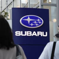 People pass by a Subaru Corp. dealership in Tokyo. The automaker\'s domestic production in January halved from a year earlier due to a factory shutdown. | KYODO