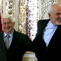 Iranian Foreign Minister Mohammad Javad Zarif (right) welcomes his Syrian counterpart, Walid Muallem, in Tehran on Tuesday. | AFP-JIJI