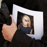 A man holds a sign honoring Sunday Times journalist Marie Colvin after a memorial service, outside St Martin in the Field in London in 2012. | REUTERS